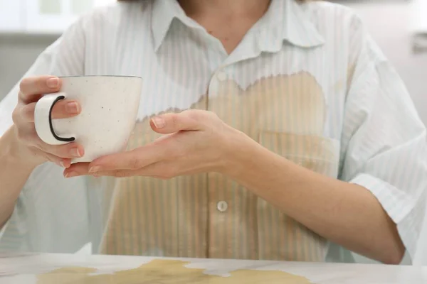 Woman with spilled coffee over her shirt at marble table indoors, closeup