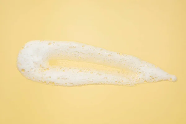 stock image Smudge of white washing foam on yellow background, top view