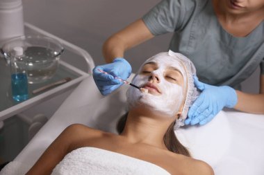 Spa salonu müşterinin yüzüne maske uygulayarak güzellik uzmanı