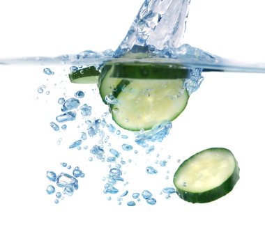 Beyaz arka planda suya düşen taze salatalık dilimleri. Yakın plan.