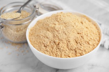 Beyaz mermer masada seramik kasede susam unu, yakın plan.