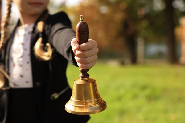Pupil holding school bell outdoors on sunny day, closeup. Space for text