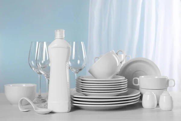 ライトグレーのテーブルの上に洗剤のきれいな食器やボトル — ストック写真