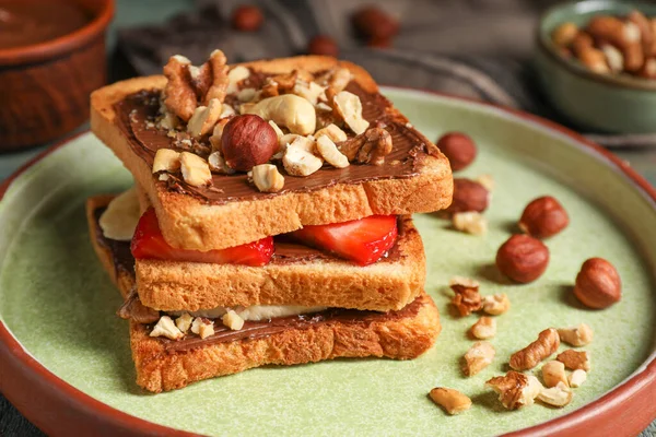 Tasty toasts with chocolate spread, nuts, strawberries and banana served on table, closeup
