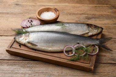 Lezzetli tuzlu ringa balığı, dereotu, soğan ve ahşap masada tuz.