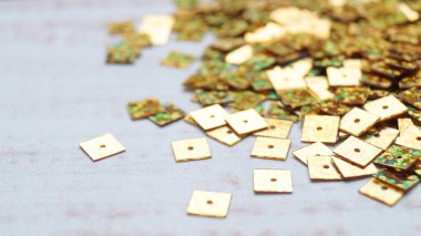 Beyaz ahşap masa üzerinde bir sürü altın payet yığını, yakın plan. Metin için boşluk