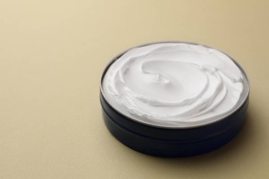 Açık yeşil arka planda bir kavanoz yüz kremi, yakın plan. Metin için boşluk