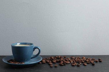 Gri masada bir fincan aromatik kahve ve fasulye. Metin için boşluk