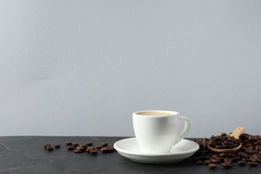 Gri masada bir fincan aromatik kahve ve fasulye. Metin için boşluk