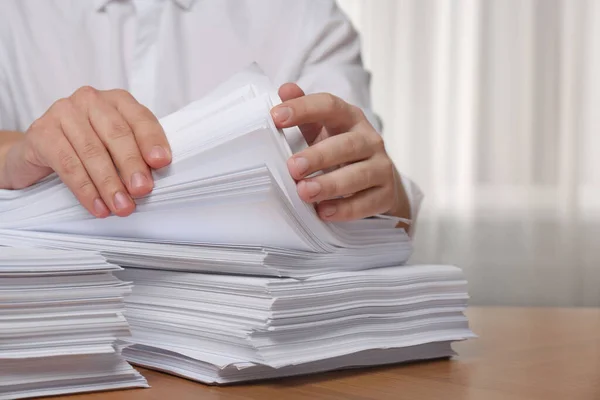 Man stacking documents at table in office, closeup