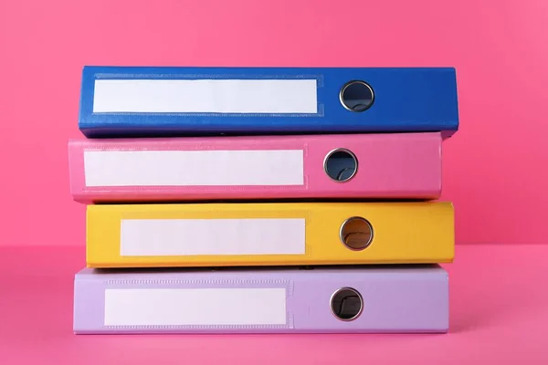 Stack of office folders on pink background