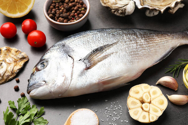 Свежая сырая рыба Дорадо, устрицы и специи на сером столе