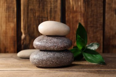 Tahta masaya istiflenmiş spa taşları ve bambu yaprakları.