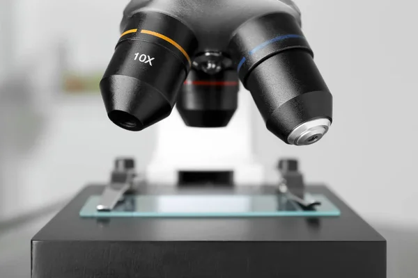 Modern medical microscope with glass slide on blurred background, closeup