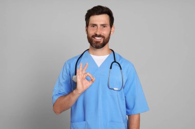 Steteskoplu doktor açık gri arka planda iyi bir jest gösteriyor.