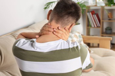 Man suffering from neck pain indoors, back view