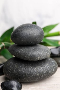 Beyaz ahşap masaya istiflenmiş spa taşları ve bambu, yakın plan.