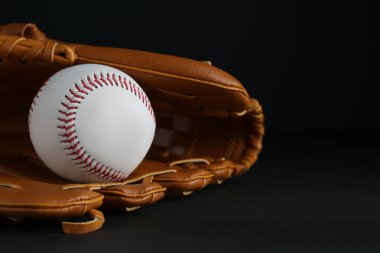 Yakalayıcı eldiveni ve siyah arka planda beyzbol topu, mesaj için boşluk. Spor oyunu