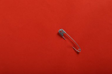 Kırmızı kağıda iliştirilmiş güvenlik iğnesi, üst manzara. Metin için boşluk