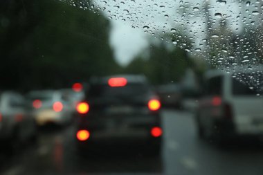 Islak arabanın penceresinden yolun bulanık görüntüsü. Yağmurlu hava