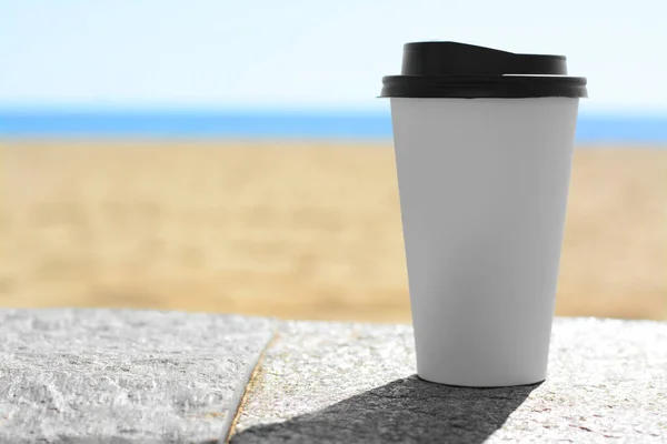 Takeaway coffee cup on stone surface outdoors. Space for text