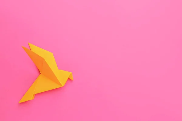 Beautiful orange origami bird on pink background, top view. Space for text