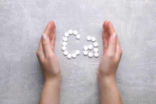 Woman and symbol Ca (Calcium) of pills on gray background, top view