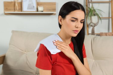 Evde ısıtma yastığı kullanan genç bir kadın.