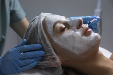 Kozmetik uzmanı, kaplıca salonunda müşterinin yüzüne maske takıyor.