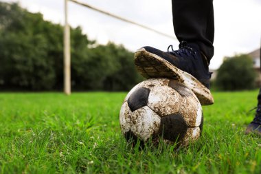 Yeşil çimlerin üzerinde kirli futbol topu olan bir adam, yakın plan. Metin için boşluk