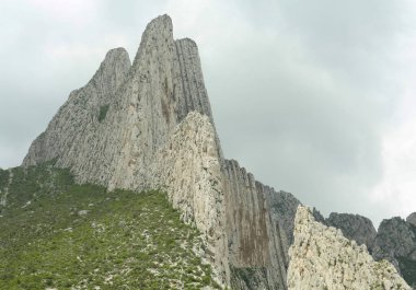 Yüksek dağları ve bulutlu gökyüzünün altında sisi olan resim gibi bir manzara.