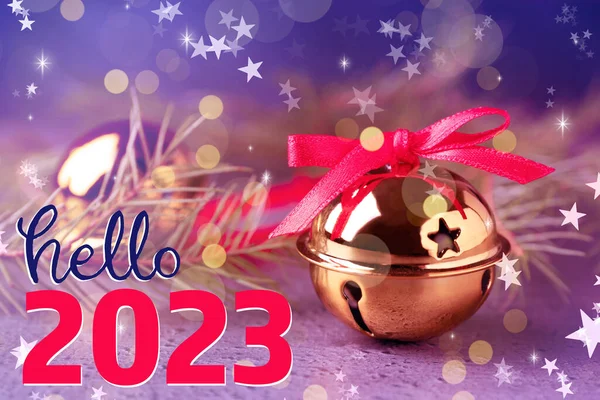 Hello 2023. Golden sleigh bells and fir branches on table, closeup