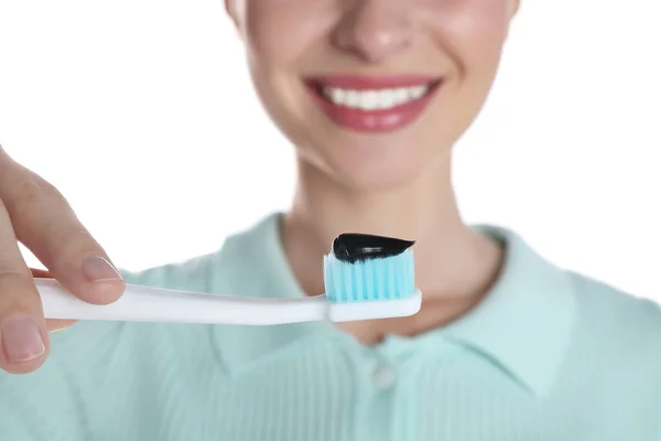 Woman holding brush with charcoal toothpaste on white background, closeup