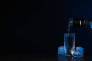 Şişeden votkayı bardağa, buzu da siyah arka plana döküyorum. Metin için boşluk