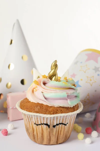 Cute sweet unicorn cupcake and party hats on white background, closeup