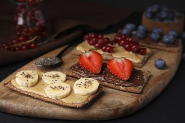 Siyah masada farklı malzemelerle taze çavdar gevreği, yakın plan.