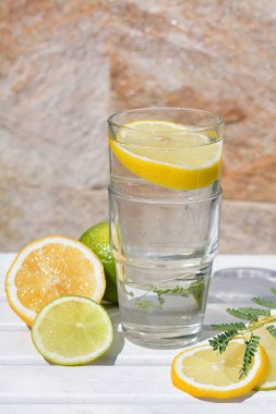 Lezzetli ferahlatıcı limonata ve beyaz ahşap masa üzerinde turunçgil parçaları.