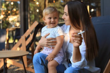 Anne sigara ve çocuk dışarıda, eliyle odaklanın. Çocukların yanında sigara içme.