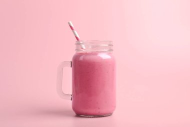 Mason kavanozu ve pembe arka planda lezzetli çilekli smoothie.
