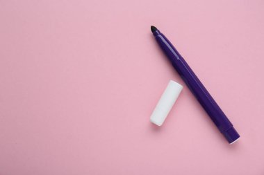 Açık pembe arka planda parlak mor kalem ve kep, düz yatıyordu. Metin için boşluk