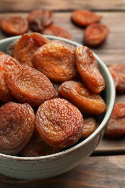 Ahşap masada bir kase lezzetli kayısı, yakın plan. Kurutulmuş meyve