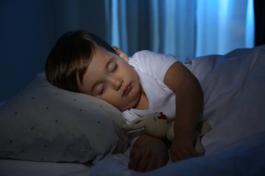 Evde oyuncakla uyuyan şirin bir bebek. Yatma zamanı.