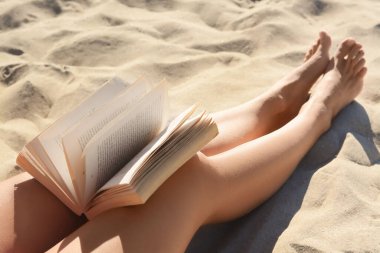 Kumsalda kitabı olan kadın, yakın plan.
