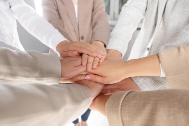 Group of people holding hands together indoors, closeup. Unity concept