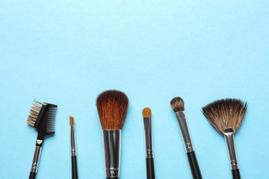 Açık mavi arka planda düz bir makyaj fırçası seti. Metin için boşluk