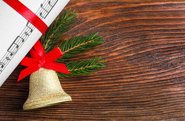 木製のテーブルの上に赤い弓と音楽シートと黄金の光沢のある鐘 フラットレイアウト テキスト用のスペース クリスマスの装飾 — ストック写真