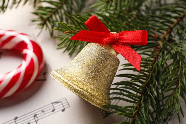 楽譜上の赤い弓とモミの枝と黄金の光沢のある鐘 クローズアップ クリスマスの装飾 — ストック写真