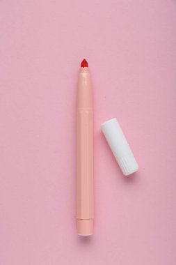 Açık pembe arka planda parlak işaret ve kapak, düz yatar