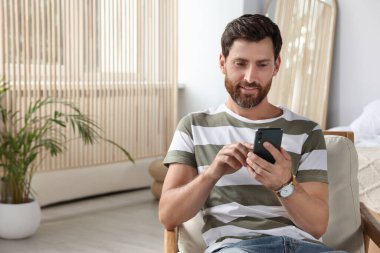 Evde akıllı telefon kullanan yakışıklı bir adam, mesaj için boşluk