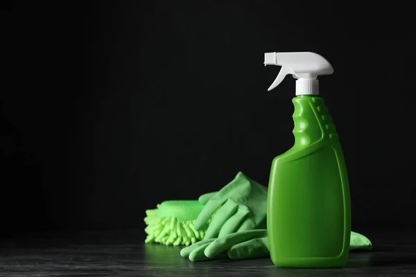 Spray bottle, rubber gloves and microfiber sponge on black table, space for text. Car products